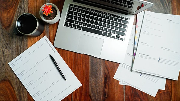 A laptop surrounded by digital workflow diagrams and business documentation.