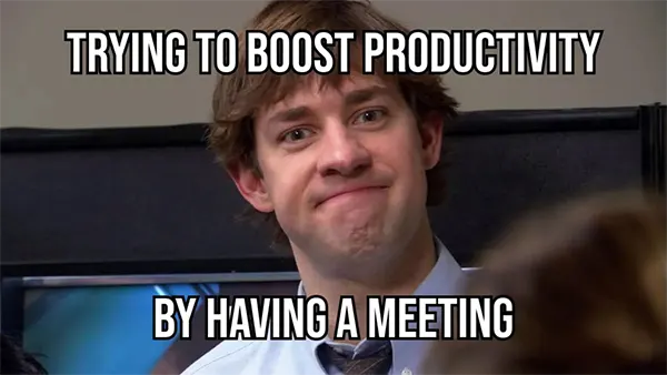 Man with a forced smile during a meeting with text “Trying to boost productivity by having a meeting.”